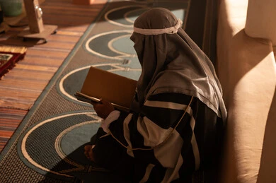 رجل سعودي بلباس تراثي يقرأ كتاباً في إضاءة دافئة