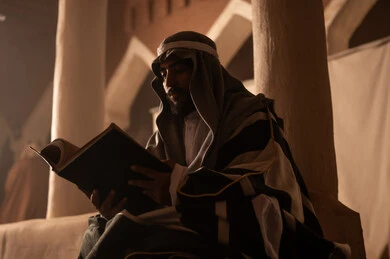 رجل سعودي يقرأ كتاباً قديماً في مبنى تراثي