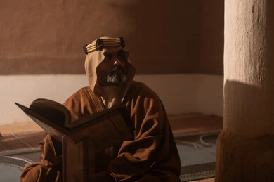 رجل سعودي يقرأ القرآن الكريم في بيت تراثي