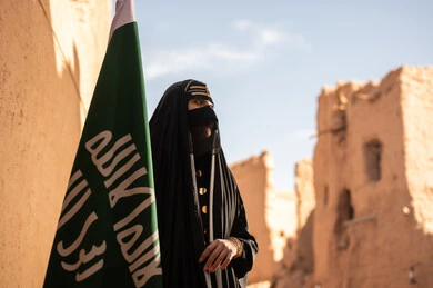 امرأة سعودية مع العلم الوطني في أطلال موقع تراثي قديم