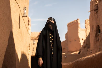 Saudi Woman in Traditional Abaya at Historic Mud Village