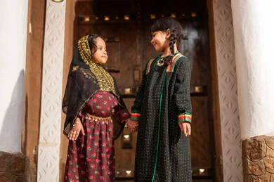 Saudi Girls in Traditional Nashal Dress by Wooden Door