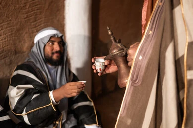 رجل سعودي بالزي الشتوي التقليدي يشرب القهوة العربية