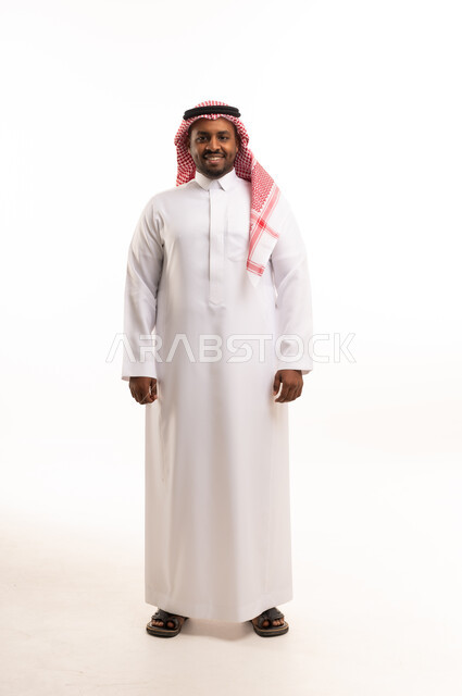 رجل سعودي بالثوب والشماغ التقليدي يقف في الاستوديو