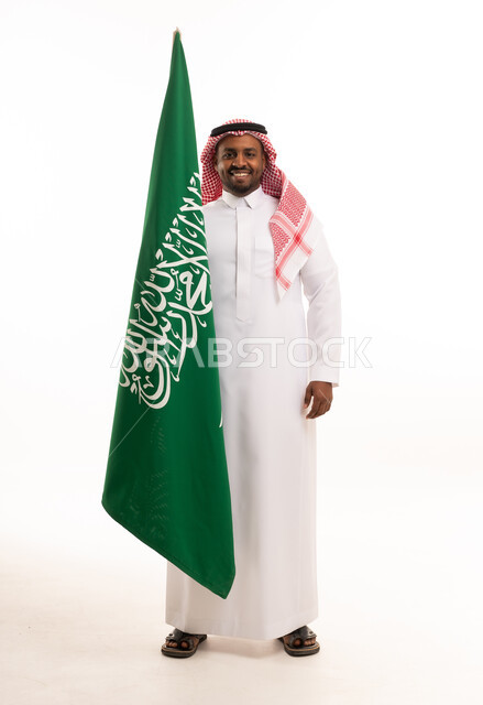 رجل سعودي يحمل العلم الوطني على خلفية بيضاء