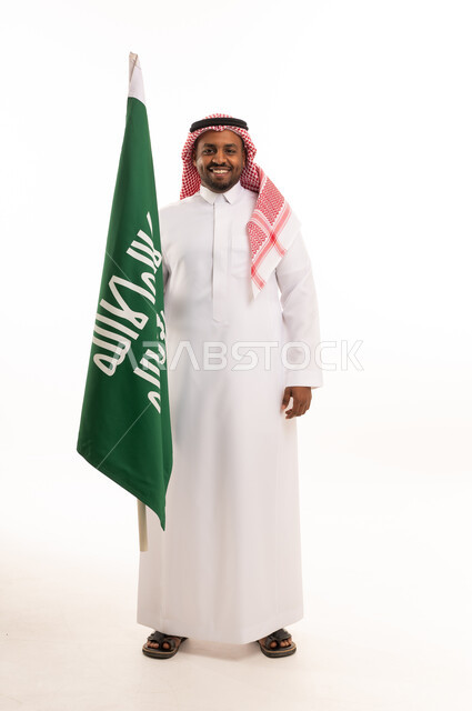 رجل سعودي بالزي التقليدي يحمل العلم الوطني