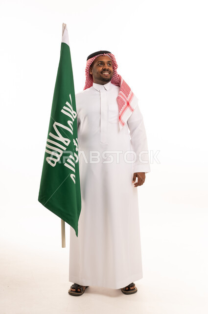 رجل سعودي يحمل علم المملكة العربية السعودية بالثوب