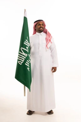 رجل سعودي يحمل علم المملكة العربية السعودية بالثوب