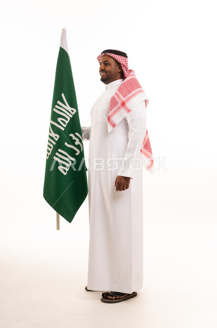 رجل سعودي يرتدي الزي التقليدي يحمل العلم