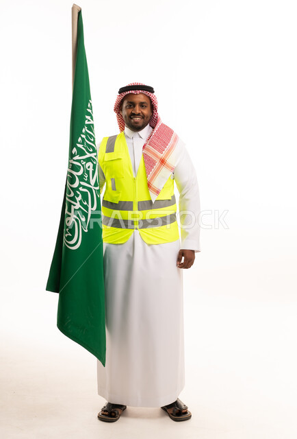 رجل سعودي بملابس السلامة يحمل علم المملكة