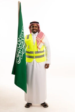 رجل سعودي بملابس السلامة يحمل علم المملكة