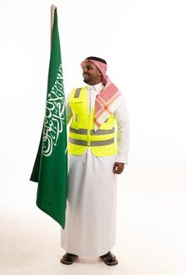 رجل سعودي بسترة سلامة يحمل علم السعودية