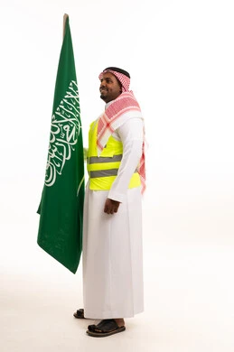 رجل سعودي بزي العمل يحمل علم المملكة العربية السعودية