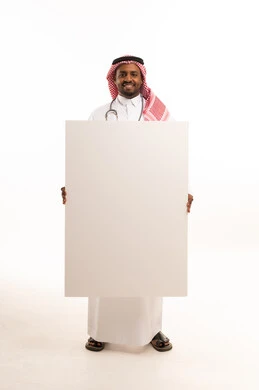طبيب سعودي يمسك بلوحة بيضاء فارغة بخلفية بيضاء