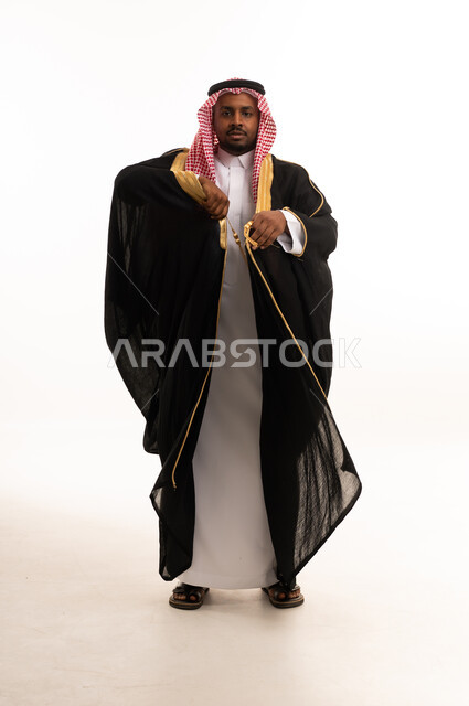 رجل سعودي بالبشت الأسود التقليدي على خلفية بيضاء