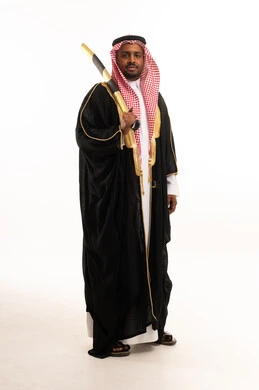 رجل سعودي بالبشت التقليدي يحمل سيفاً
