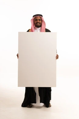 رجل سعودي يحمل لوحة بيضاء فارغة في استوديو