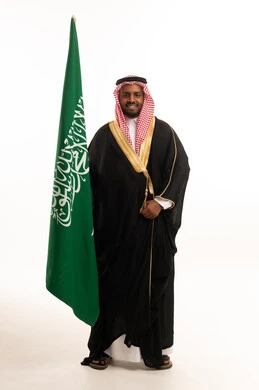 Saudi Man in Traditional Bisht Standing with Saudi Flag