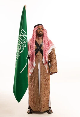 رجل سعودي يحمل العلم الوطني بزي العرضة
