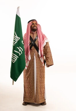 رجل سعودي بالزي التقليدي يحمل العلم الوطني