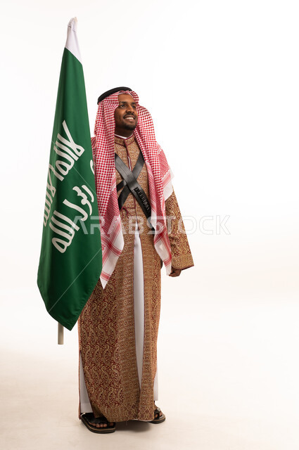 Saudi Man Holding Saudi Flag in Traditional Dress