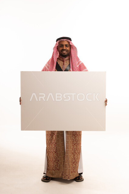 رجل سعودي يمسك لوحة بيضاء فارغة في الاستوديو