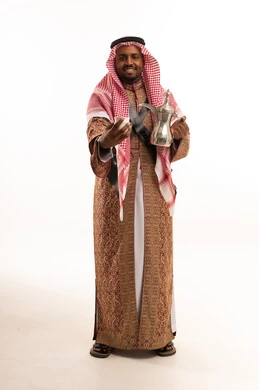 رجل سعودي بالزي التقليدي والبشت يمسك دلة قهوة