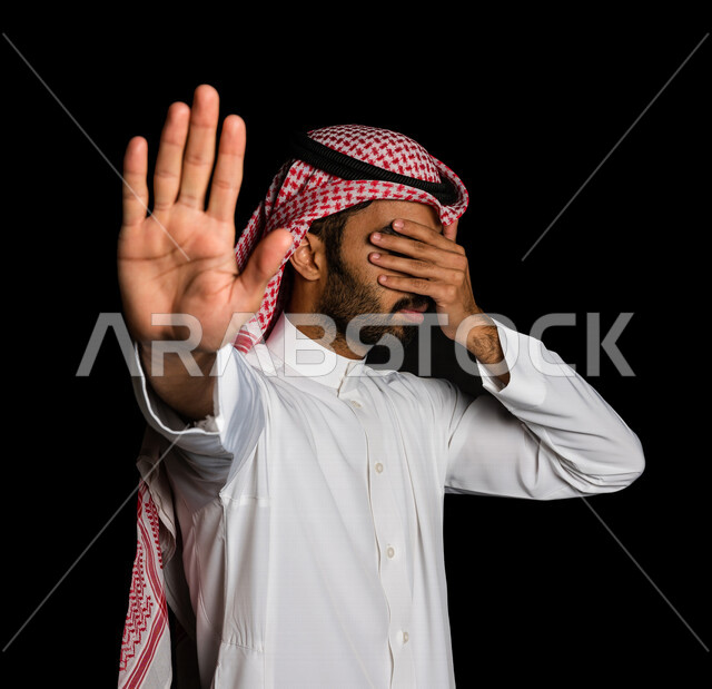 رجل عربي سعودي خليجي يرتدي الزي السعودي, إيماءات يدين تدل على الأمر بالتوقف عن فعل شيء ما, النهي عنه, الشعور بالإنزعاج, الرفض والإمتناع, خلفيه سوداء