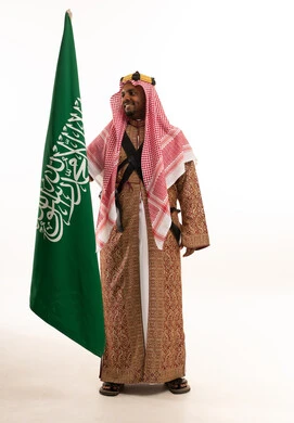 رجل سعودي مع العلم الوطني بالدقلة التقليدية