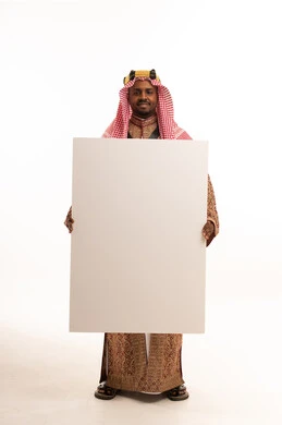 رجل سعودي بالزي الشعبي التقليدي يحمل لوحة بيضاء فارغة