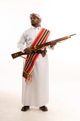 رجل سعودي بالزي الشعبي الجنوبي يحمل بندقية تراثية