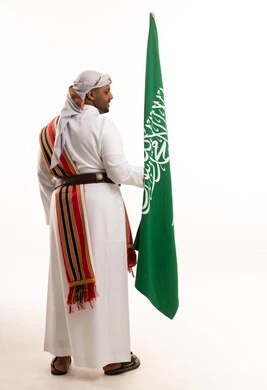 رجل سعودي بزي العرضة التقليدي يحمل العلم