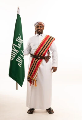 رجل سعودي يحمل العلم بالزي التقليدي والجنابية