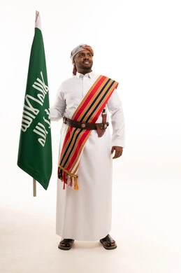 رجل سعودي يحمل العلم بالزي النجدي التقليدي