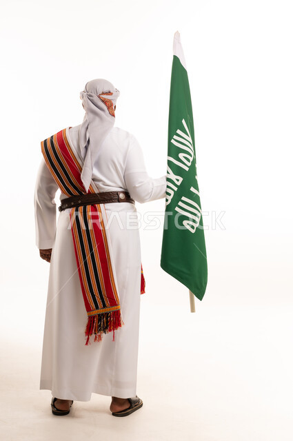 رجل سعودي يحمل العلم الوطني بالزي التقليدي