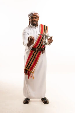 رجل سعودي بالزي الجيزاني التقليدي يحمل دلة قهوة