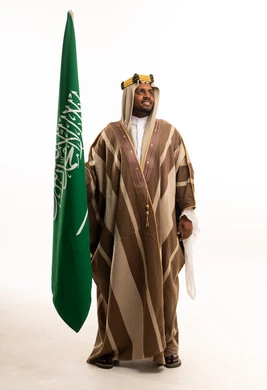 رجل سعودي يحمل العلم الوطني بالزي التقليدي