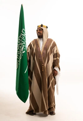 رجل سعودي مع العلم الوطني السعودي يرتدي البشت التقليدي