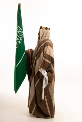 رجل سعودي بالزي التقليدي يحمل علم السعودية