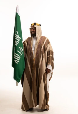 رجل سعودي يحمل العلم الوطني السعودي بالزي التقليدي
