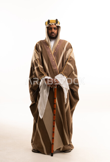 رجل سعودي بالبشت التقليدي يحمل عصا خشبية