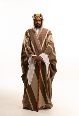 رجل سعودي بالبشت التقليدي يحمل عصا خشبية