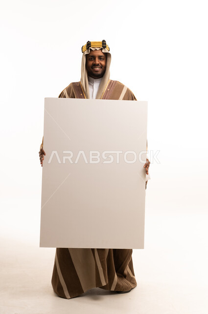 رجل سعودي يحمل لوحة بيضاء فارغة في الاستوديو