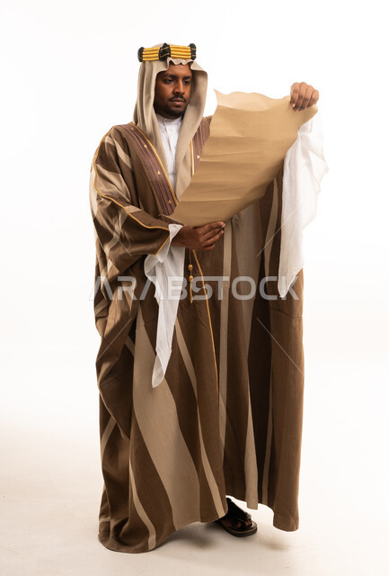 رجل سعودي بالزي التقليدي يقرأ مخطوطة قديمة