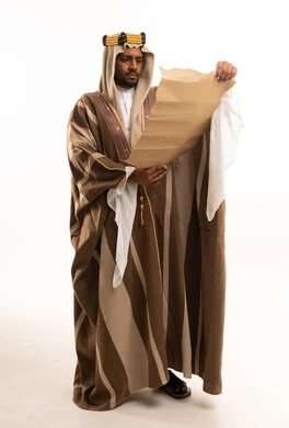 رجل سعودي بالزي التقليدي يقرأ مخطوطة قديمة