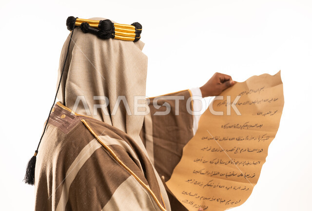 رجل سعودي بالبشت التقليدي يحمل مخطوطة قديمة