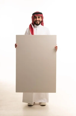 رجل سعودي يحمل لوحة بيضاء فارغة في الاستوديو