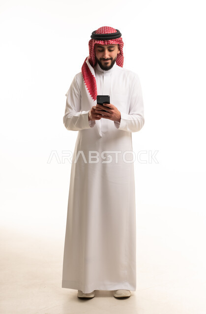رجل سعودي بالثوب التقليدي يستخدم الهاتف الذكي