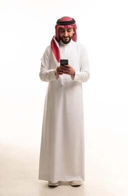 رجل سعودي بالثوب التقليدي يستخدم الهاتف الذكي