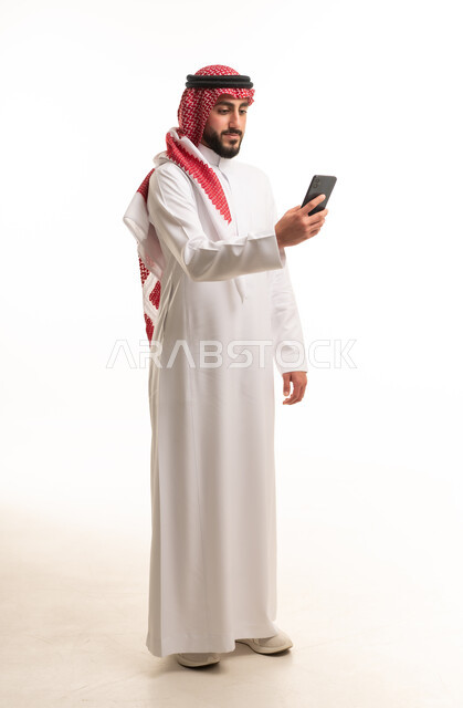 رجل سعودي بالثوب التقليدي يستخدم الهاتف الذكي